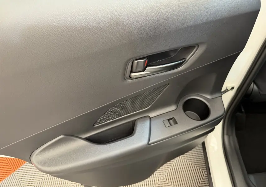 Gros plan sur la porte avant droite blanche du Toyota C-HR 1.8 Hybride 140 Dynamic avec poignée et rangement intégré.