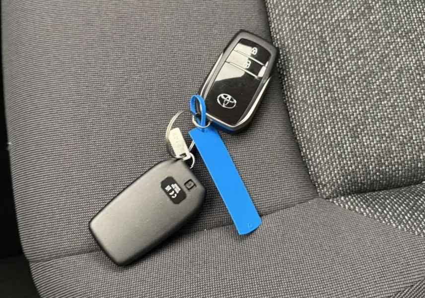 Clé Toyota noire posée sur siège tissu gris foncé à motifs, intérieur du Toyota C-HR 1.8 Hybride 140 Dynamic 2024.