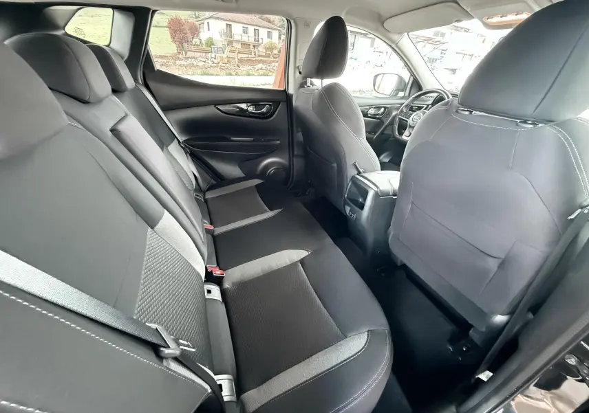 Vue intérieure arrière côté droit du Nissan Qashqai 2020 noir, sièges tissu noir avec détails gris et ceintures visibles.