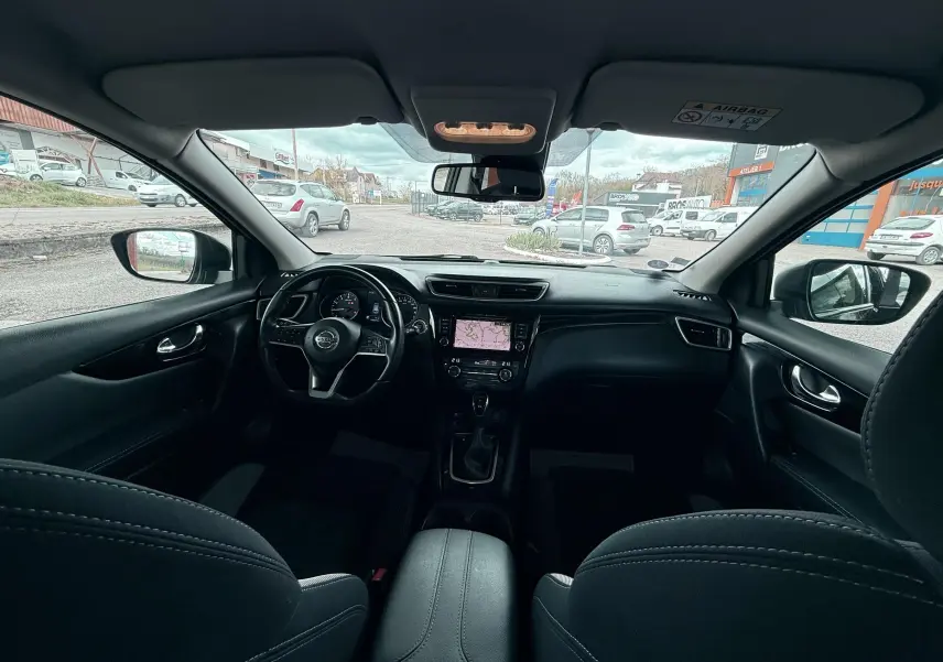 Vue intérieure avant du Nissan Qashqai noir 2020, avec tableau de bord et écran tactile central visibles.