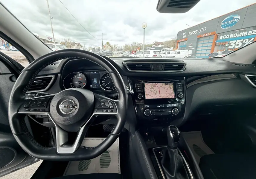 Vue intérieure du tableau de bord et volant Nissan Qashqai noir avec écran tactile affichant la navigation.