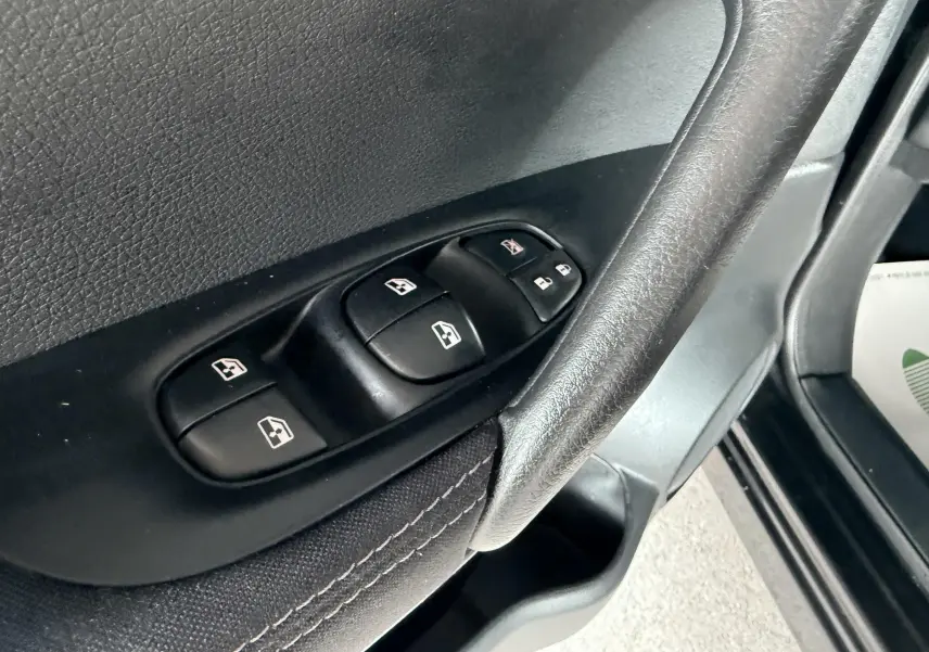 Gros plan sur les commandes de lève-vitres et verrouillage sur la porte avant gauche du Nissan Qashqai noir.