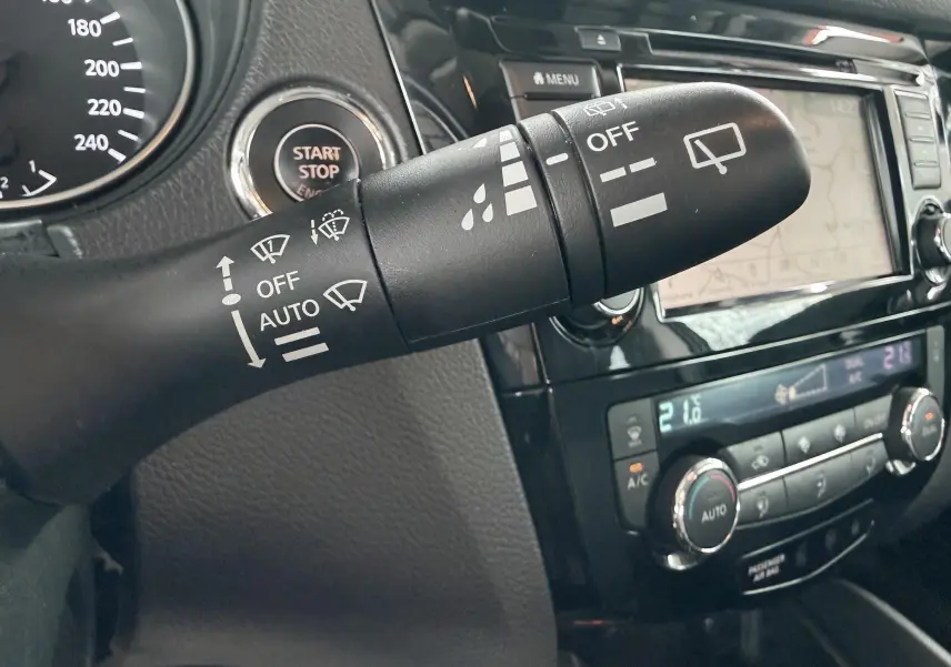 Gros plan sur la commande d’essuie-glace dans l’habitacle noir du Nissan Qashqai, avec tableau de bord et écran tactile en arrière-plan.