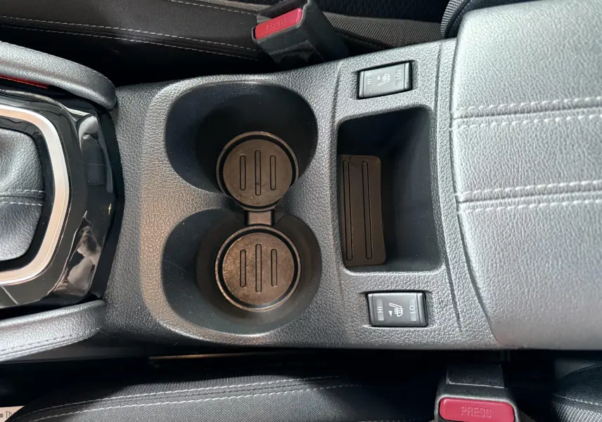 Gros plan sur la console centrale noire du Nissan Qashqai 2020 avec porte-gobelets et commandes de sièges chauffants.