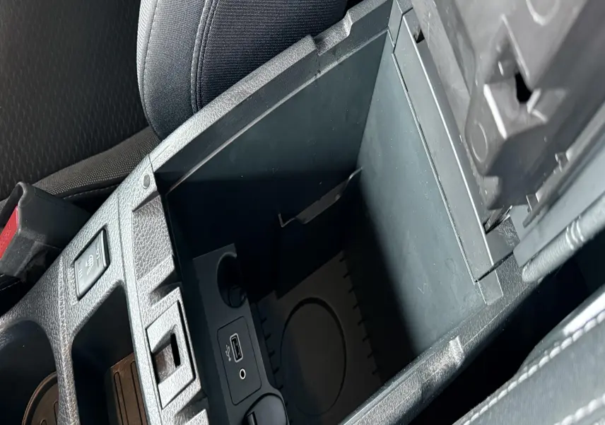 Vue rapprochée de la console centrale ouverte du Nissan Qashqai noir, montrant les ports USB et prise 12V.