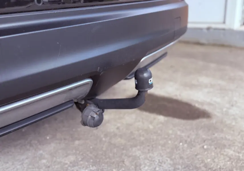 Gros plan sur l'attelage de remorque fixé au pare-chocs arrière noir d'un Nissan Qashqai.