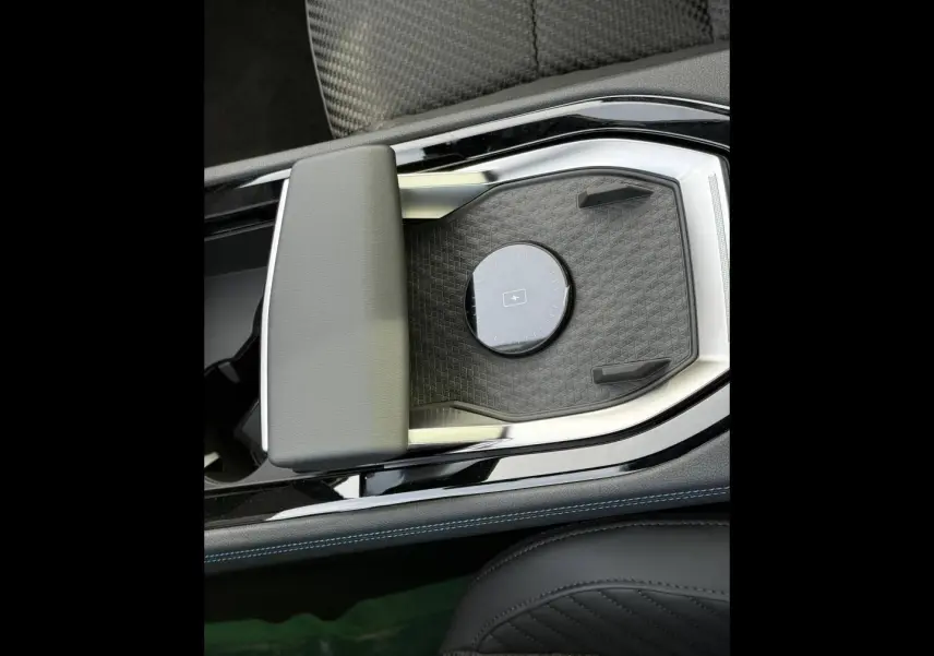 Vue rapprochée de la console centrale noire avec accoudoir gris et surface de recharge sans fil du Renault Austral 2026.