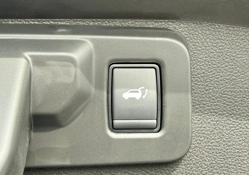 Bouton intérieur de commande d'ouverture électrique du coffre sur Renault Austral 2026, plastique gris texturé.