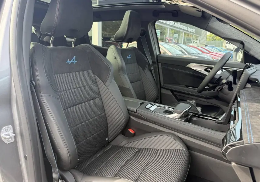 Vue intérieure côté conducteur du Renault Austral 2026, sièges noirs en Alcantara avec logo Alpine bleu brodé.