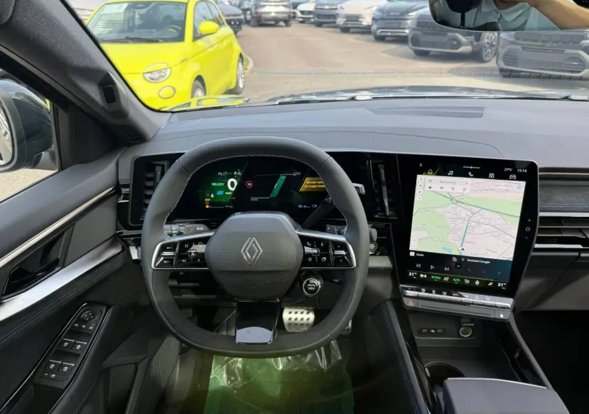 Vue intérieure frontale du tableau de bord du Renault Austral gris, avec volant multifonction et écran tactile vertical.