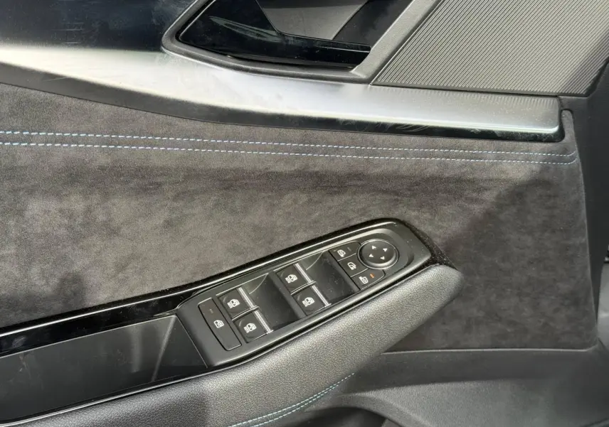Gros plan sur la porte côté conducteur du Renault Austral 2026, revêtement gris foncé avec surpiqûres bleues et commandes vitres.