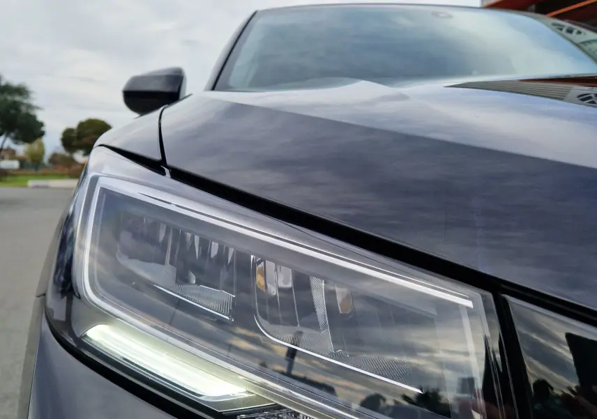 Gros plan sur le phare avant gauche d'un Audi Q2 35 TFSI noir mito metal, mettant en valeur ses lignes modernes et LED.