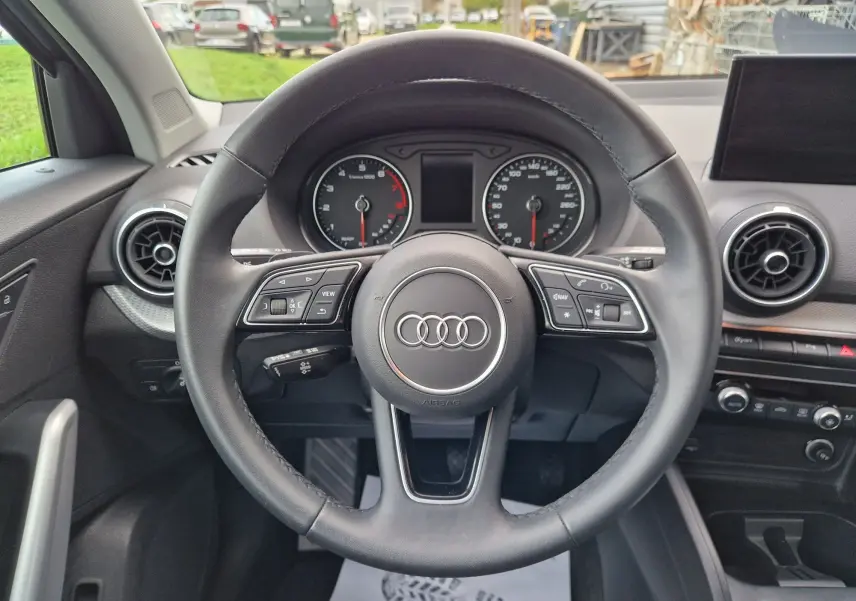 Vue centrée sur le volant cuir de l'Audi Q2 35 TFSI 2023, avec tableau de bord et aérateurs ronds visibles.
