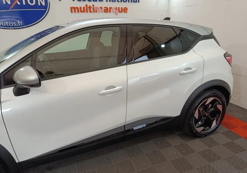 Profil côté gauche du Renault Captur blanc 2025, avec jantes noires et détails noirs sur les bas de caisse.