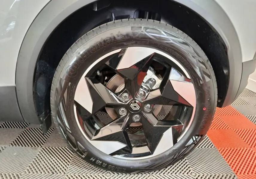 Gros plan sur la roue avant droite du Renault Captur blanc, jante noire et argentée au design géométrique distinctif.