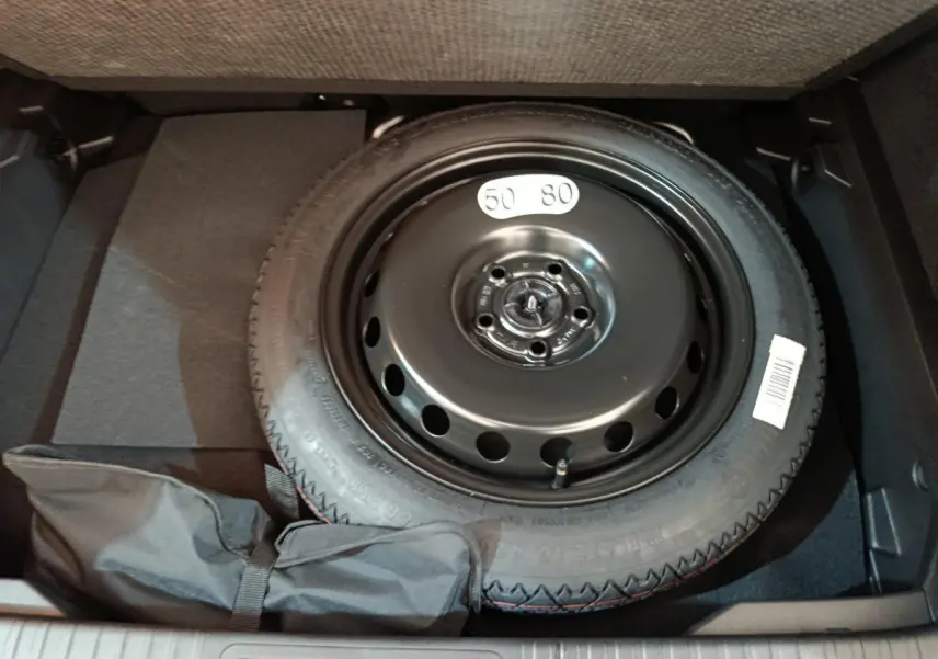 Vue rapprochée de la roue de secours noire dans le coffre du Renault Captur blanc techno E-Tech 2025.