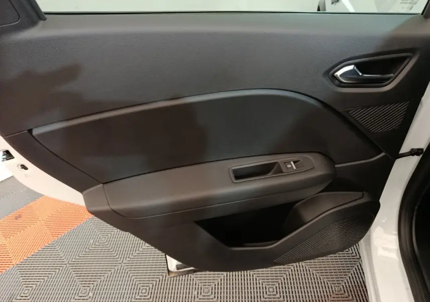 Intérieur de la porte côté droit du Renault Captur blanc 2025, avec poignée et commande de vitre noire.