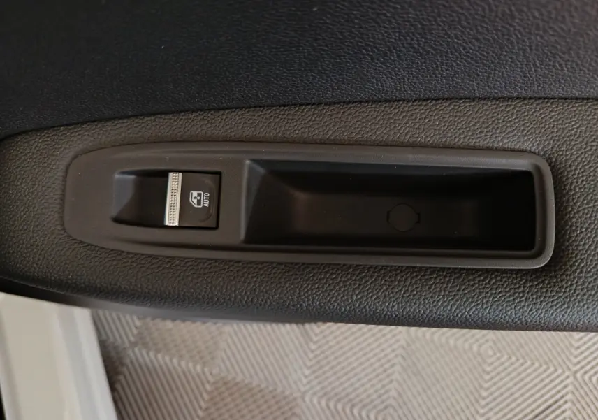 Détail de la commande de lève-vitre électrique côté conducteur sur porte intérieure noire du Renault Captur blanc 2025.