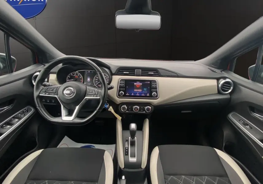 Vue intérieure avant de la Nissan Micra 2022, tableau de bord beige et noir avec volant multifonction et écran tactile central.