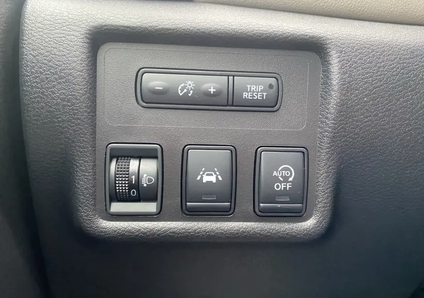 Panneau de commandes noir mat avec réglage luminosité, bouton de suivi de voie et désactivation automatique, intérieur Nissan Micra 2022.