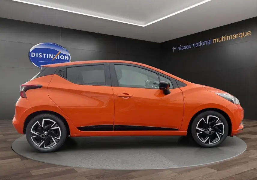 Vue latérale droite d'une Nissan Micra 2022 orange Energy avec jantes noires et détails noirs sur les bas de caisse.