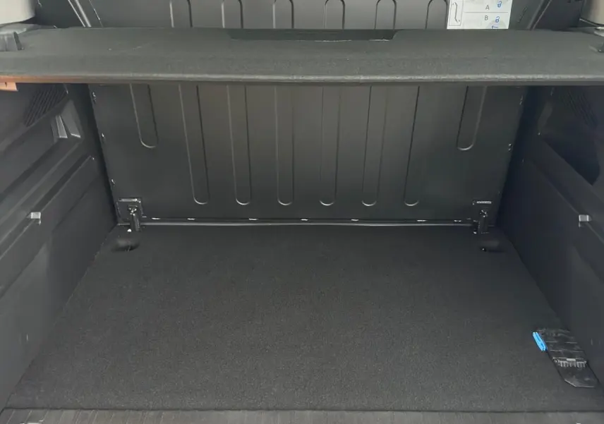 Vue intérieure arrière du coffre gris du Citroën Berlingo N1 2025 avec séparation grillagée et tablette de rangement.