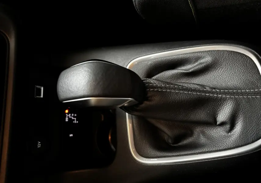 Gros plan sur le levier de vitesses automatique noir de la Citroën C3 PureTech 110 Shine, avec coutures visibles.