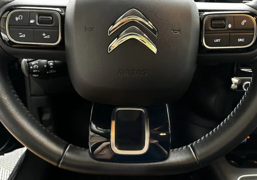 Gros plan sur le volant noir multifonctions de la Citroën C3 2024 avec commandes intégrées et logo chromé central.