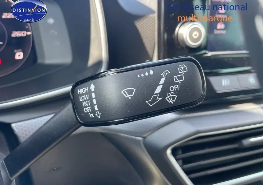 Gros plan sur la commande d'essuie-glace du SEAT LEON IV gris magnétique, avec tableau de bord et écran tactile en arrière-plan.