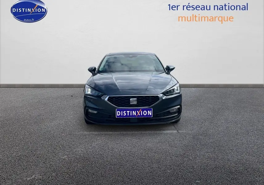 Vue frontale d'une SEAT Leon IV gris magnétique métal avec calandre hexagonale et phares LED allumés.