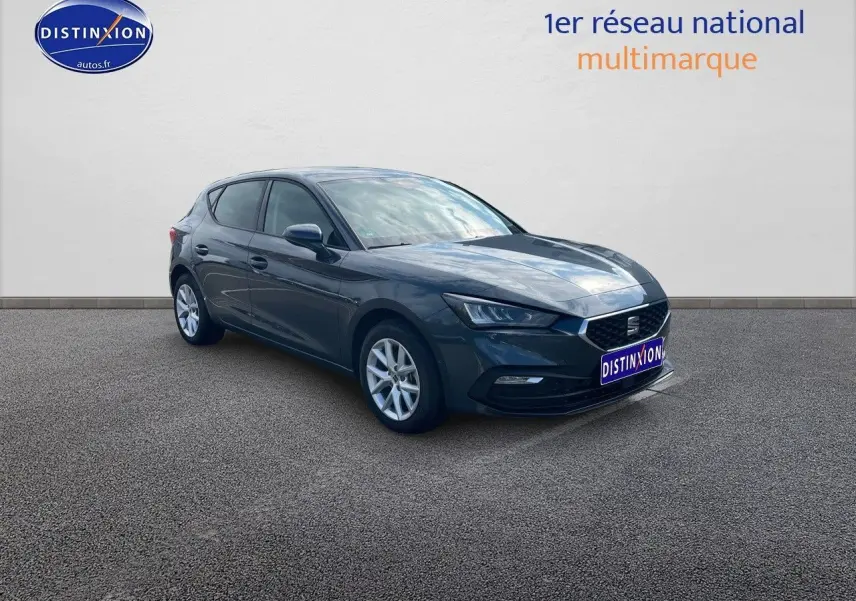 SEAT LEON IV gris magnétique métal en vue 3/4 avant droit, avec jantes argentées et phares LED allumés.
