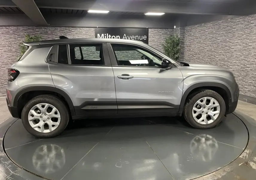 Vue de profil côté gauche d'un Jeep Avenger gris métallisé avec jantes alliage 17 pouces en showroom.