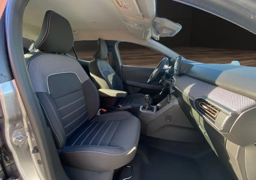 Vue intérieure côté conducteur de la Dacia Sandero Stepway 2025 gris schiste, sièges noirs et tableau de bord moderne.