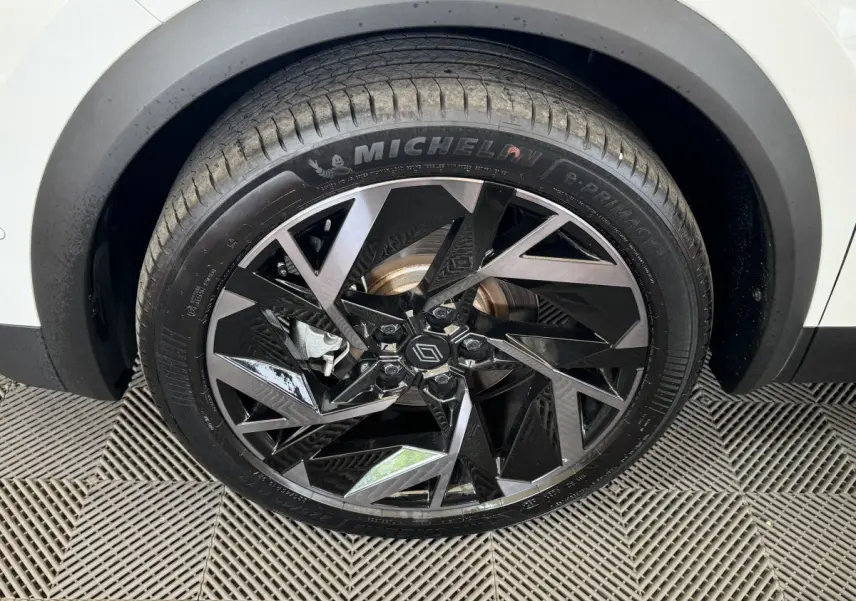 Gros plan sur la roue avant droite du Renault Captur blanc esprit Alpine avec jante noire et argentée au design géométrique.