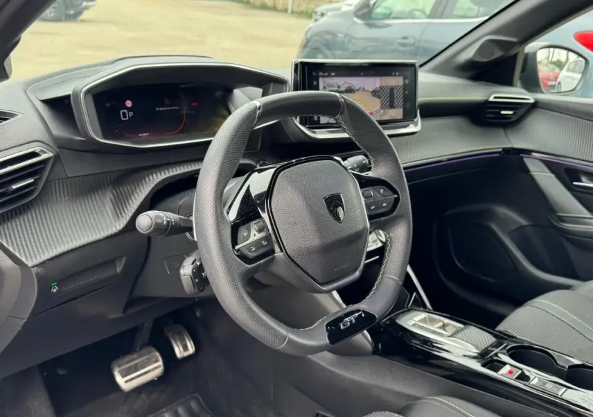 Vue intérieure côté conducteur du Peugeot 208 Hybrid 110 e-DCS6 GT 2025, volant compact GT et écran tactile central.