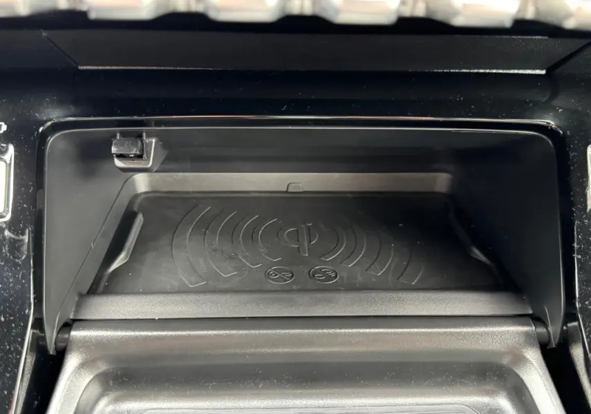 Gros plan sur le compartiment de recharge sans fil du Peugeot 208 Hybrid 110 e-DCS6 GT gris, intérieur noir.