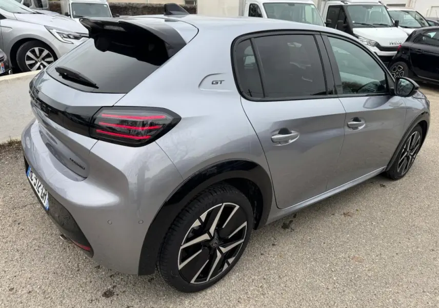 Vue 3/4 arrière droite d'une Peugeot 208 Hybrid 110 GT grise avec jantes alliage 17 pouces et toit noir brillant.