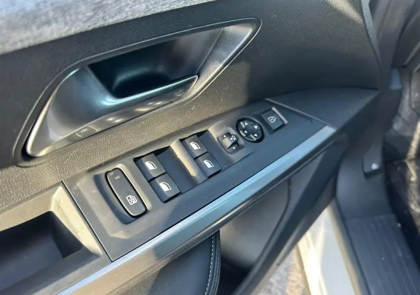 Détail des commandes de lève-vitres et rétroviseurs sur la porte avant gauche d’un Peugeot 3008 blanc 2025.