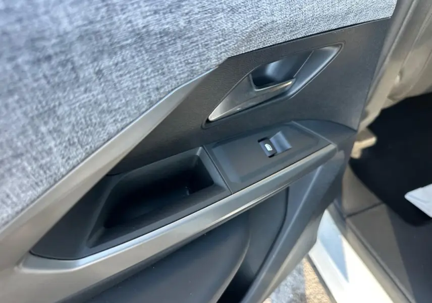 Gros plan sur la porte intérieure côté gauche du Peugeot 3008 blanc, montrant la poignée et la commande de vitre.