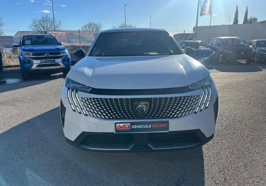 Vue avant d’un Peugeot 3008 Hybrid blanc avec calandre distinctive et feux LED verticaux allumés.