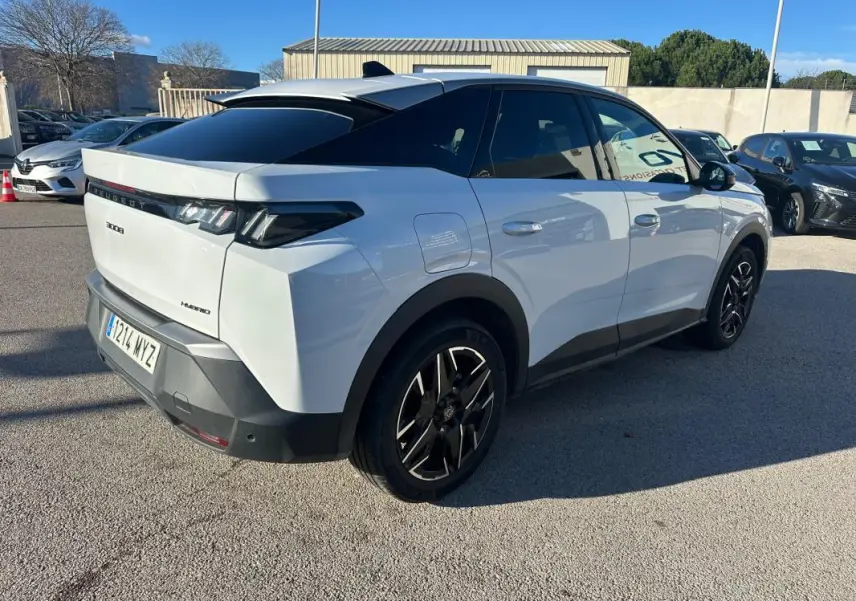 Vue 3/4 arrière droite d’un Peugeot 3008 Hybrid blanc avec jantes alliage noires 19 pouces et toit noir.