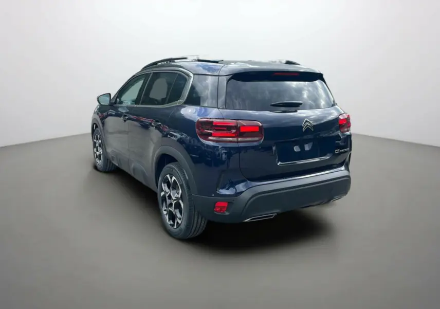 Vue 3/4 arrière gauche d'un Citroën C5 Aircross 2025 hybride bleu Eclipse avec toit noir et jantes stylisées.