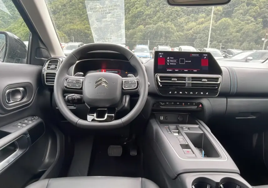 Intérieur du Citroën C5 Aircross Hybrid 2025 vu de face, avec tableau de bord noir et écran tactile central.
