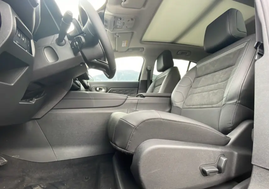 Intérieur avant du Citroën C5 Aircross Hybrid 2025, sièges en cuir noir et toit ouvrant panoramique visible.
