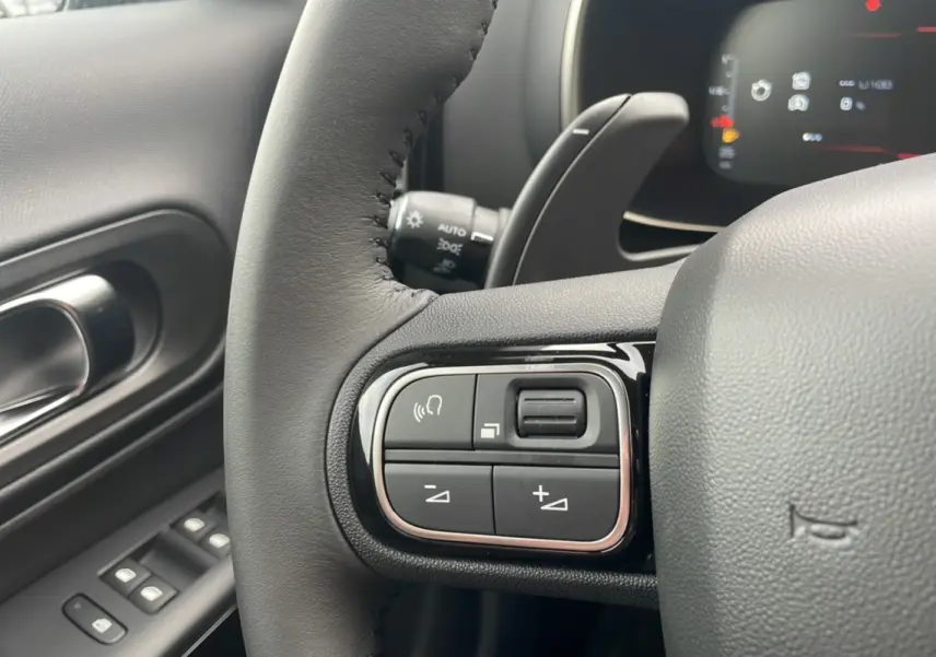 Gros plan sur les commandes au volant du Citroën C5 Aircross Hybrid 2025, intérieur noir avec détails chrome.