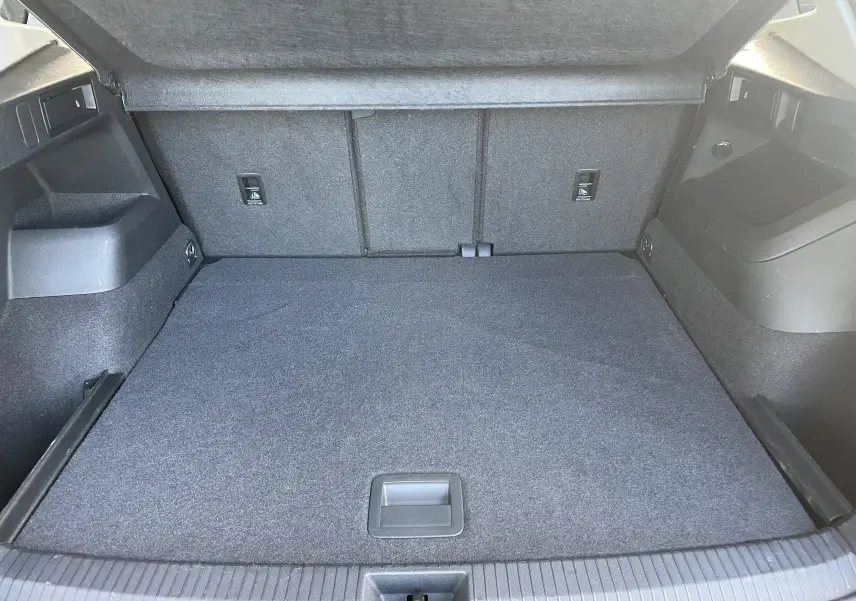 Coffre ouvert vu de l'arrière d'un Volkswagen Tiguan 2024, intérieur gris noir avec revêtement tissu.