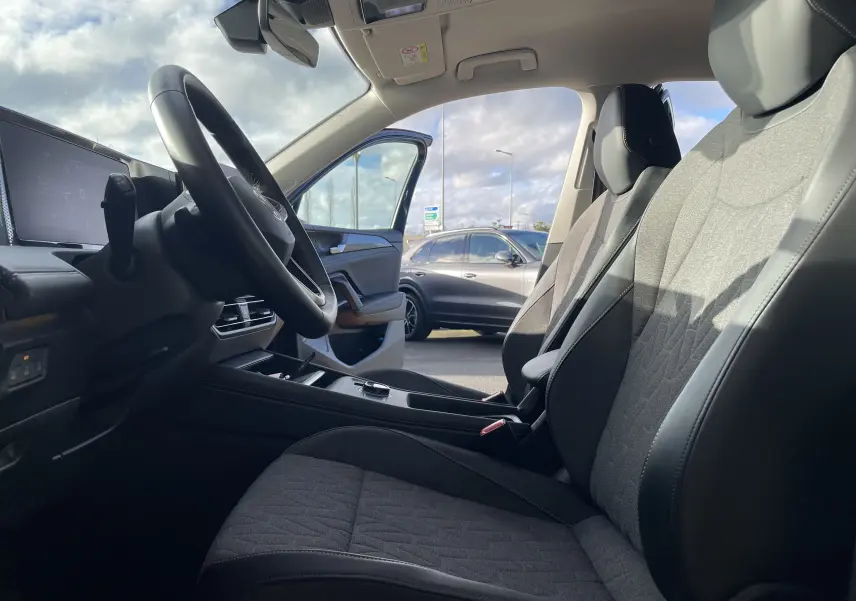 Vue intérieure côté conducteur du Volkswagen Tiguan 2024 bleu Nightshade, sièges gris-noir et volant cuir visible.