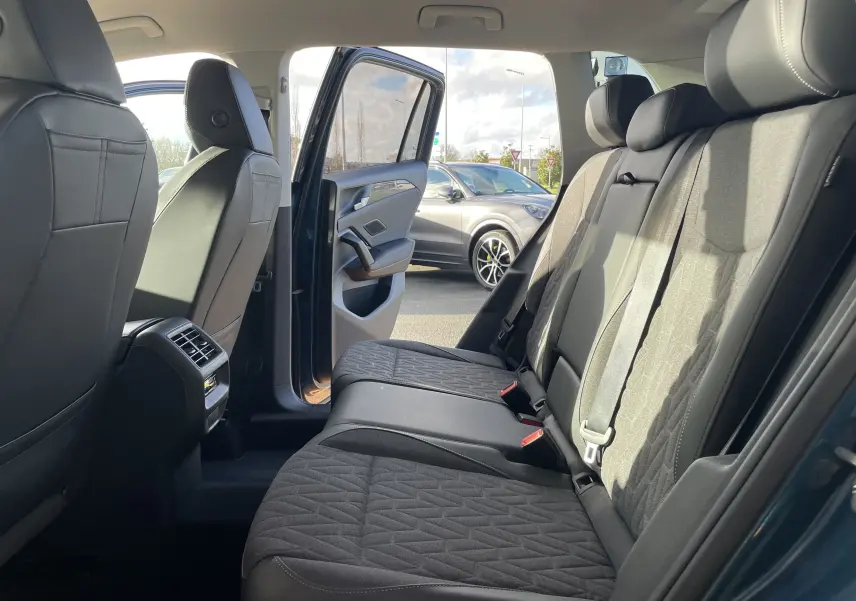 Vue intérieure côté droit sur la banquette arrière du Volkswagen Tiguan 2024 bleu Nightshade avec portes ouvertes.