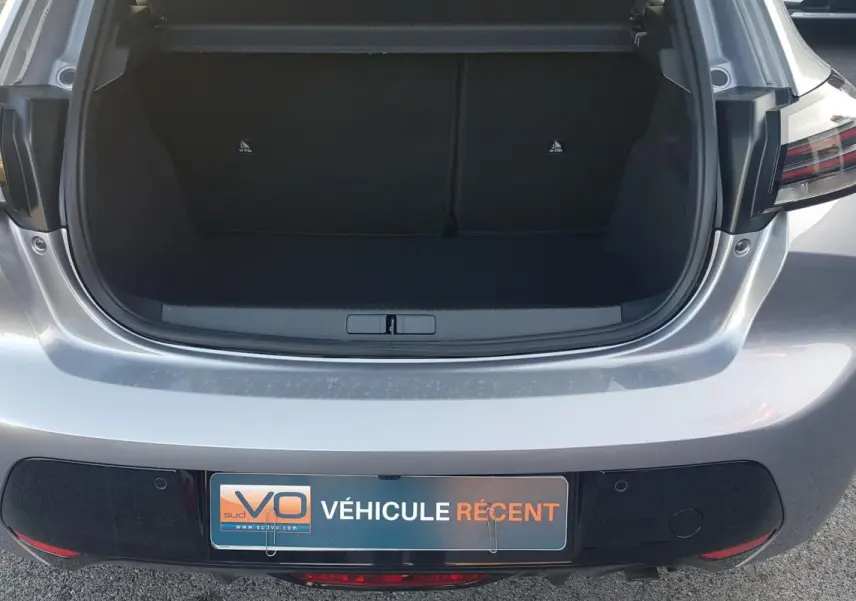 Vue arrière ouverte sur le coffre d’une Peugeot 208 Hybrid 110 gris, avec feux arrière LED et plaque VÉHICULE RÉCENT.