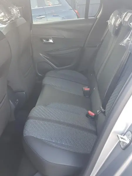 Vue intérieure de la banquette arrière droite de la Peugeot 208 Hybrid 110 gris, sièges en tissu et cuir avec ceintures rouges.